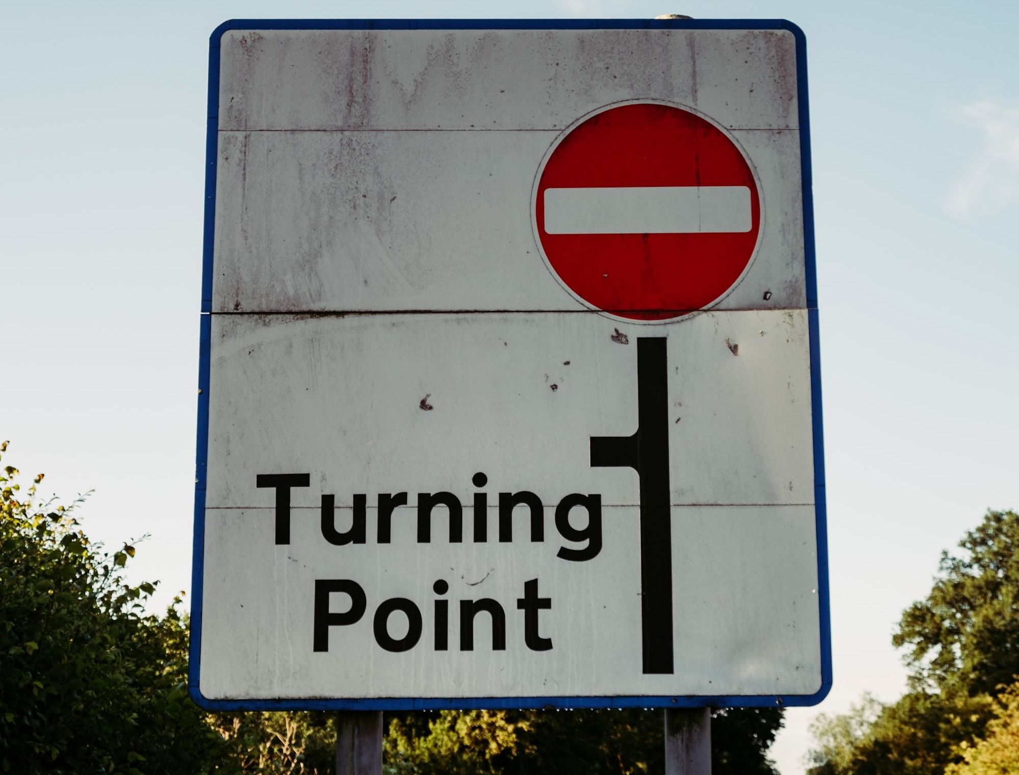 A traffic sign reads "turning point" on a street in the daytime.