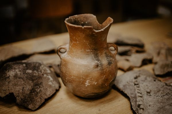A pottery artefact stands among shards of other broken pots.